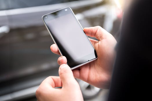 Close-up of hands holding a smartphone outdoors during the day.
