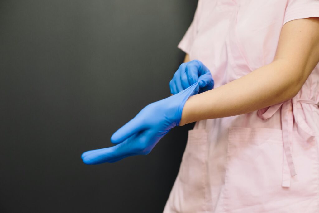 Close-up of a healthcare worker putting on blue medical gloves for protection.